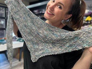 smiling woman is holding handknit shawl