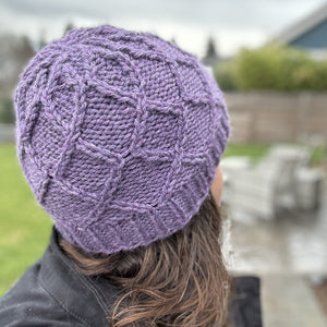 closeup of cable stitches of handknit hat modeled by a woman