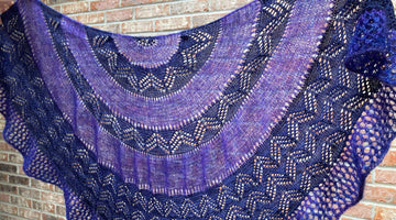 purple lace shawl displayed against a brick wall