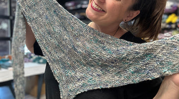 smiling woman is holding handknit shawl