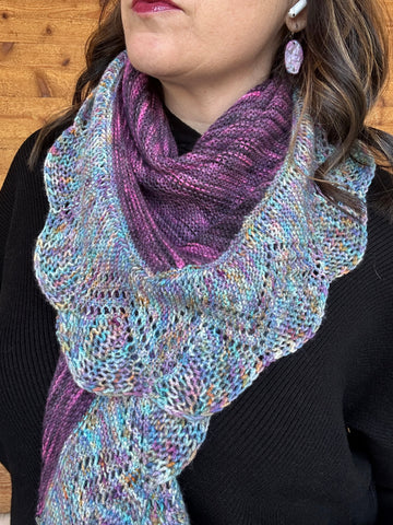 closeup image of 2-color lace-edged  handknit shawl modeled by a woman