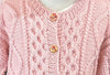 closeup image of the fabric of a pink cable textured cardigan handknit baby sweater