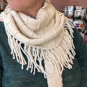 closeup image of elongated triangle shaped, fringed  handknit shawl modeled on a woman