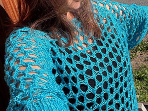 closeup image of the knit fabric of a summery lace mesh tee modeled on a woman