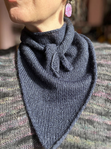 closeup image of the fabric of a dark blue kerchief handknit scarf