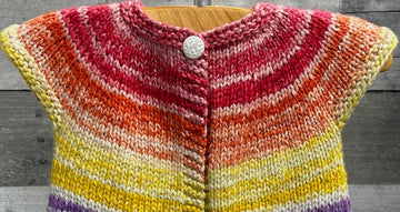 closeup image of the fabric of a rainbow striped cardigan handknit baby sweater