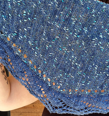 closeup image of a textured fabric and lace edge on a handknit shawl top