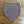 A hand-knitted cowl with a purple and cream houndstooth pattern, laid flat on a wooden floor.