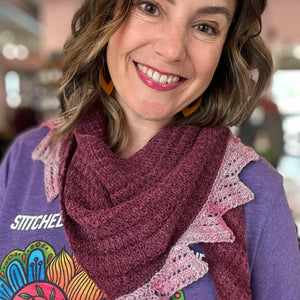 Woman wearing a purple scarf with a colorful patterned shirt in an indoor setting